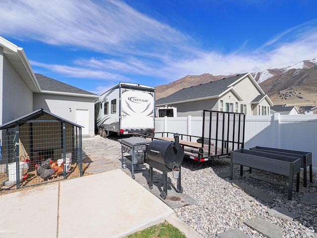 view of patio / terrace featuring a mountain view, an outdoor structure, a grill, and a fenced backyard