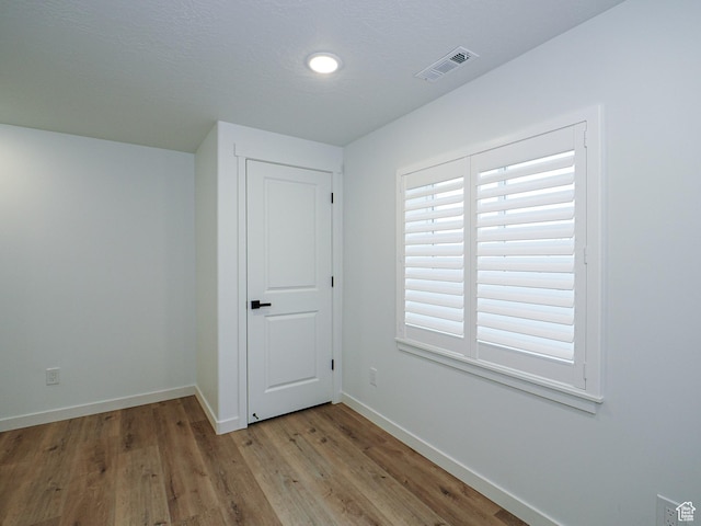 empty room featuring visible vents, baseboards, and light wood finished floors