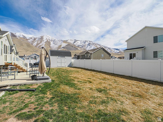 view of yard featuring an outdoor structure, a patio area, a mountain view, and a shed