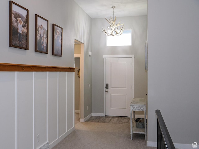 entrance foyer with baseboards, a notable chandelier, and carpet flooring