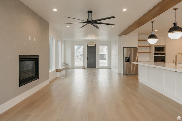 994 W Union Bench Dr S, Mapleton, UT 84664 - unfurnished living room with light wood-type flooring, a glass covered fireplace, and recessed lighting