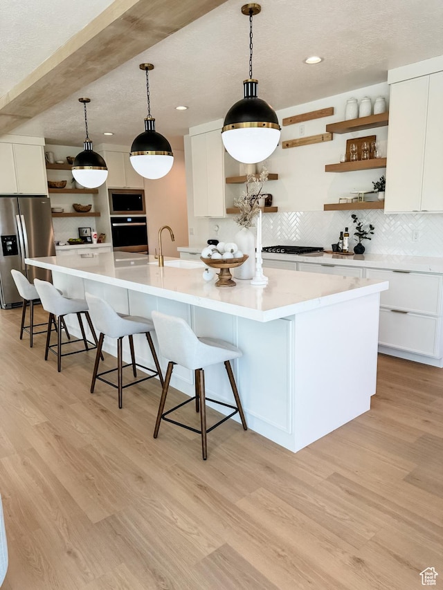 994 W Union Bench Dr S, Mapleton, UT 84664 - kitchen with light wood finished floors, open shelves, appliances with stainless steel finishes, and a spacious island