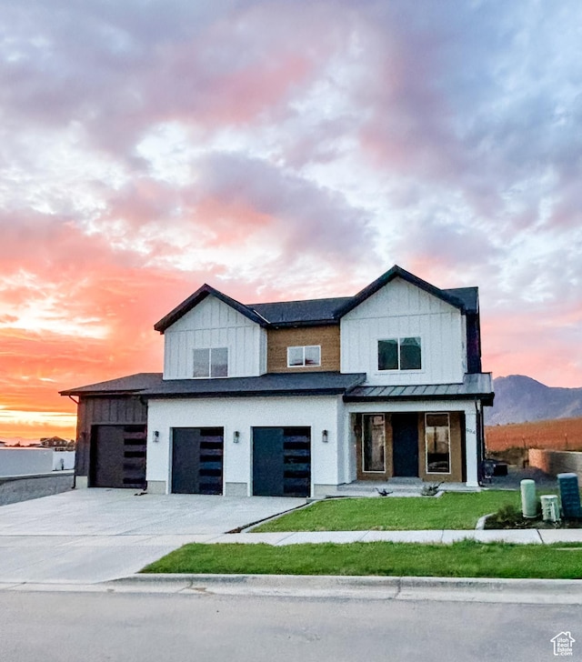 view of front of house featuring a garage, concrete driveway, a front lawn, and board and batten siding