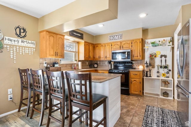 440 W Cottonwood Ln, Ferron, UT 84523 - kitchen featuring appliances with stainless steel finishes, a kitchen bar, kitchen peninsula, and decorative backsplash
