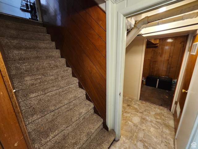 stairs featuring wood walls