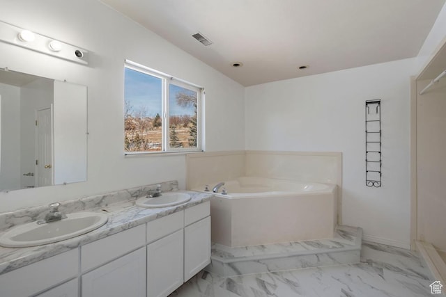 full bathroom featuring a garden tub, double vanity, marble finish floor, and a sink