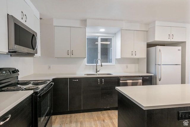 kitchen featuring a sink, stainless steel appliances, light countertops, white cabinets, and light wood-style floors