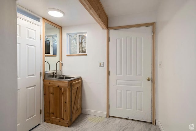bar featuring indoor wet bar, baseboards, and a sink