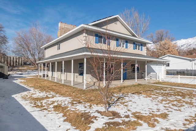 view of front of home with a porch, stucco siding, fence, and a chimney