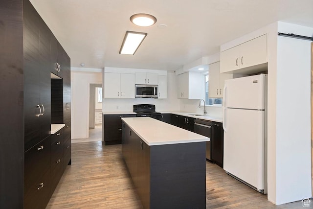 kitchen featuring light wood-type flooring, a sink, a center island, stainless steel appliances, and light countertops