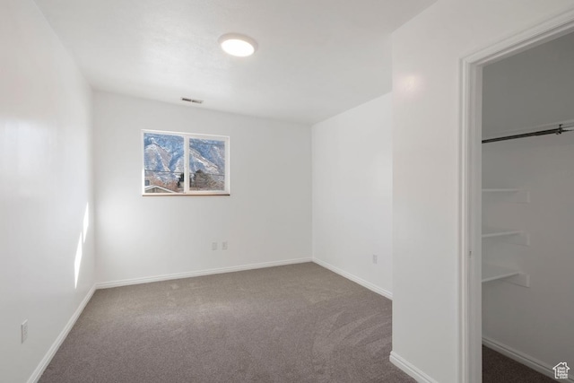 unfurnished bedroom featuring visible vents, a walk in closet, baseboards, carpet flooring, and a closet