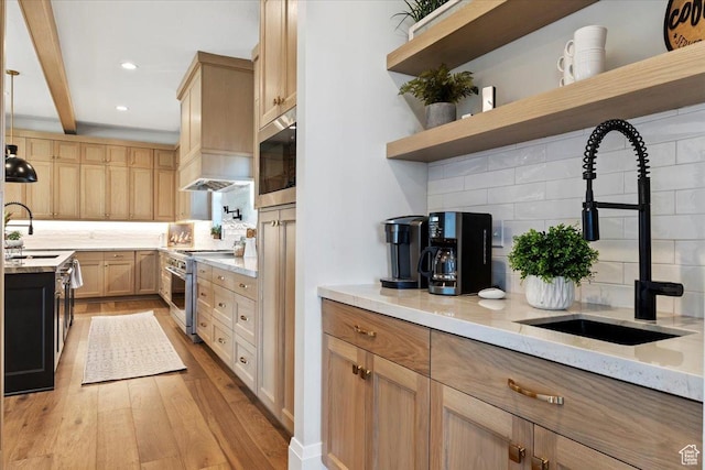 kitchen featuring appliances with stainless steel finishes, sink, decorative backsplash, and light hardwood / wood-style flooring