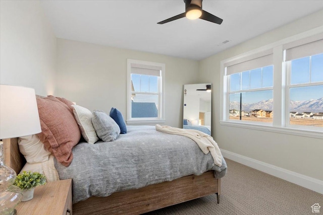 carpeted bedroom with a mountain view and ceiling fan
