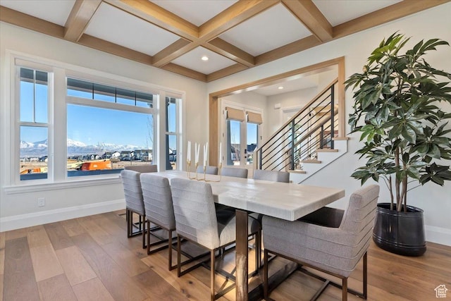 dining room with coffered ceiling, a mountain view, light hardwood / wood-style floors, and beamed ceiling