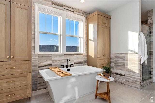 bathroom with a bathing tub, tile walls, and tile patterned floors
