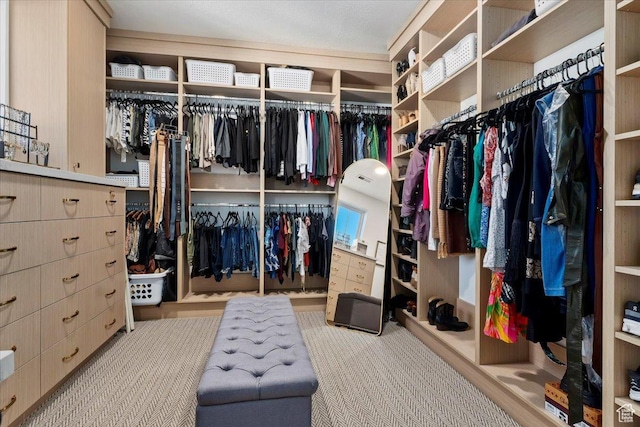 walk in closet with light carpet