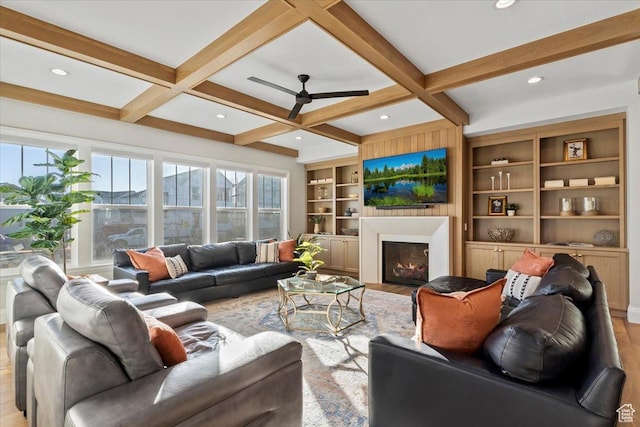 living room featuring coffered ceiling, built in shelves, and plenty of natural light