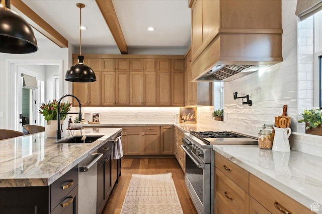 kitchen featuring pendant lighting, sink, a kitchen island with sink, stainless steel appliances, and light stone counters