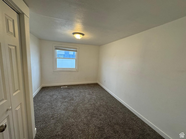 carpeted empty room featuring a textured ceiling