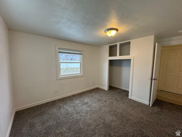 unfurnished bedroom with dark carpet and a textured ceiling