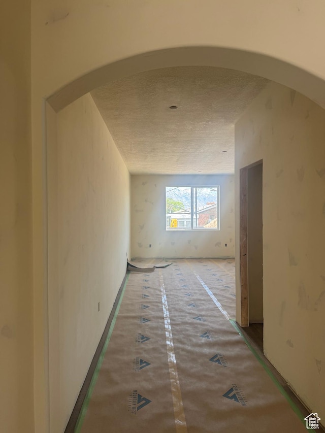 hallway with arched walkways and a textured ceiling