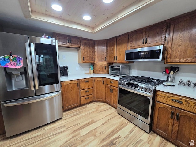 4556 W 4950 S, Hooper, UT 84315 - kitchen with a tray ceiling, appliances with stainless steel finishes, light countertops, brown cabinets, and light wood finished floors