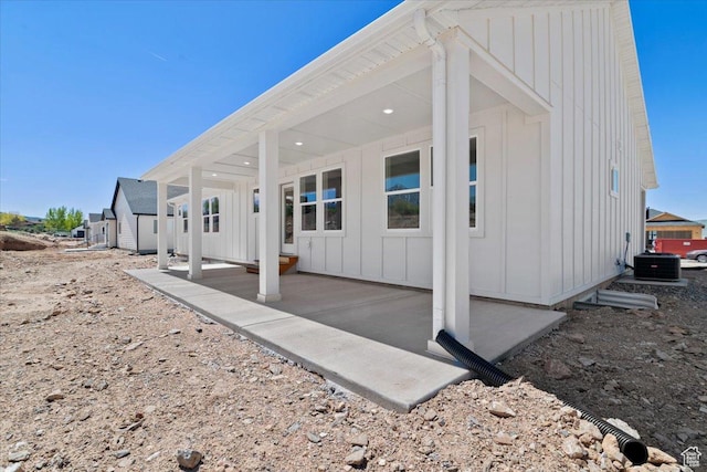 back of property featuring board and batten siding, a patio, and central AC unit