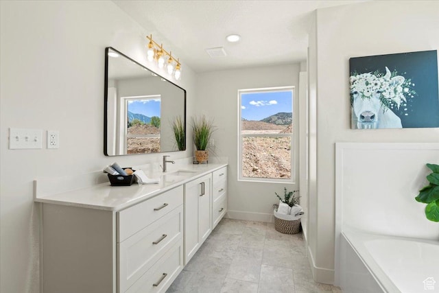 bathroom featuring vanity, baseboards, a bathtub, and plenty of natural light