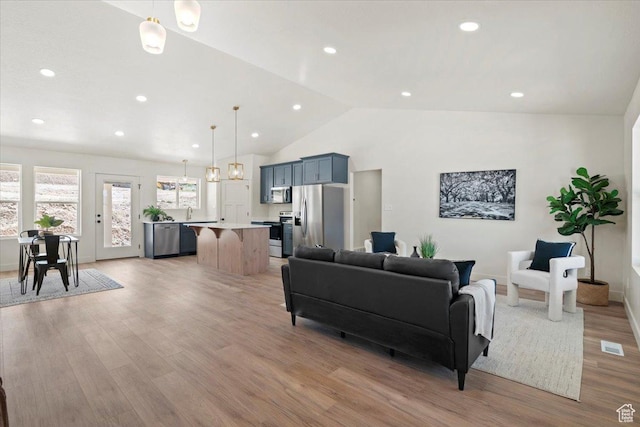 living room with light wood finished floors, lofted ceiling, visible vents, and recessed lighting