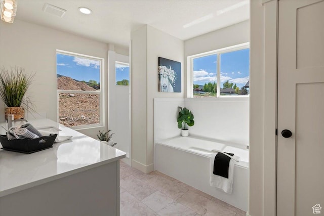 full bath with baseboards, a garden tub, recessed lighting, and plenty of natural light
