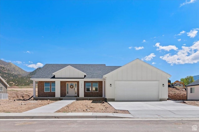 view of front of house with board and batten siding, brick siding, a garage, and driveway