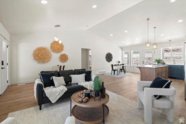 living room featuring lofted ceiling, baseboards, light wood-style flooring, and recessed lighting