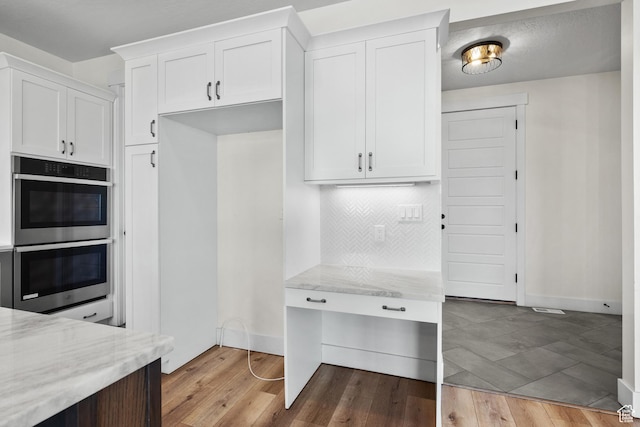 1002 W Temple Rim Ln, Payson, UT 84651 - kitchen featuring double oven, white cabinetry, backsplash, light hardwood / wood-style floors, and light stone countertops
