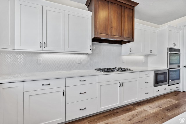 1002 W Temple Rim Ln, Payson, UT 84651 - kitchen with white cabinetry, appliances with stainless steel finishes, backsplash, and light hardwood / wood-style flooring