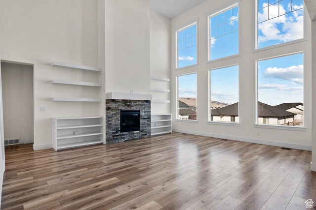 1002 W Temple Rim Ln, Payson, UT 84651 - unfurnished living room with hardwood / wood-style flooring, a towering ceiling, built in features, and a fireplace