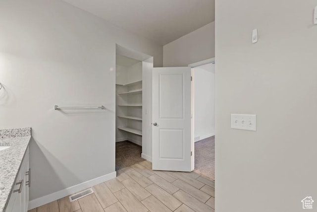 bathroom featuring visible vents, baseboards, vanity, and wood tiled floor