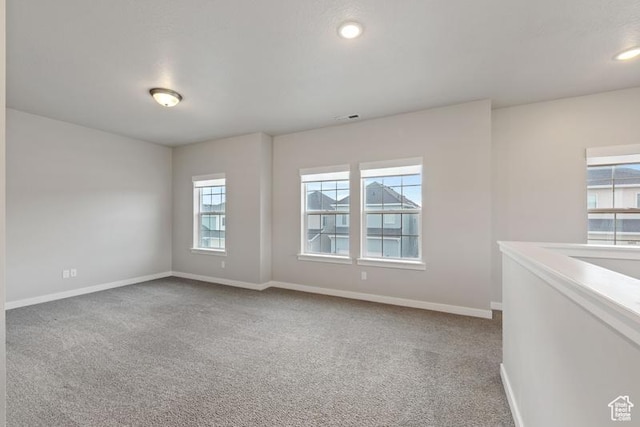 carpeted spare room featuring visible vents and baseboards