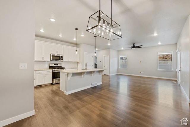 kitchen with baseboards, white cabinetry, ceiling fan with notable chandelier, dark wood-type flooring, and stainless steel appliances