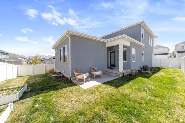 rear view of property featuring a yard, a fenced backyard, central AC unit, and stucco siding
