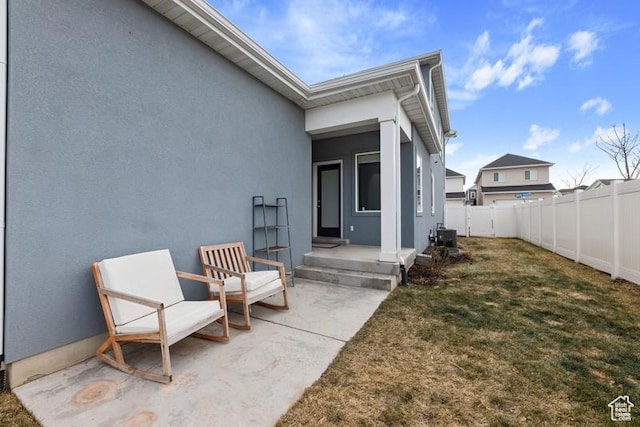 doorway to property with stucco siding, fence, and a lawn