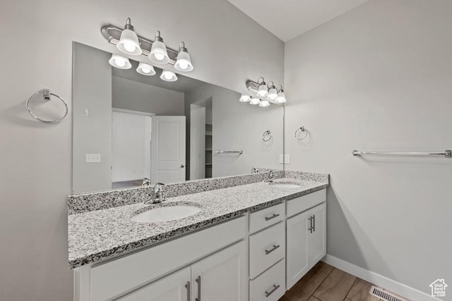bathroom featuring a sink, visible vents, baseboards, and double vanity