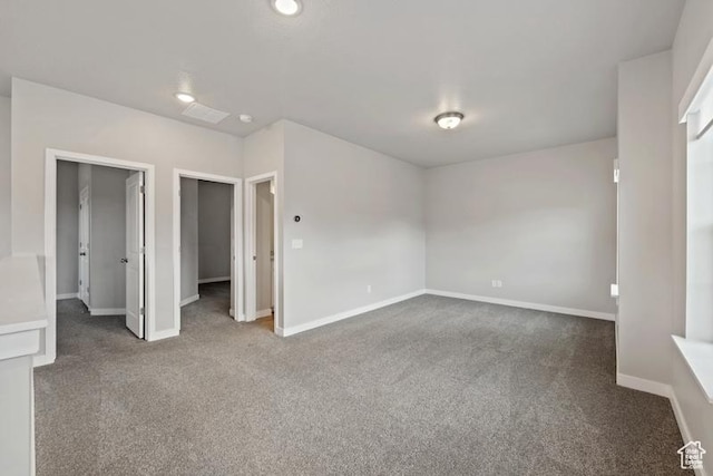 unfurnished bedroom with a walk in closet, baseboards, and carpet