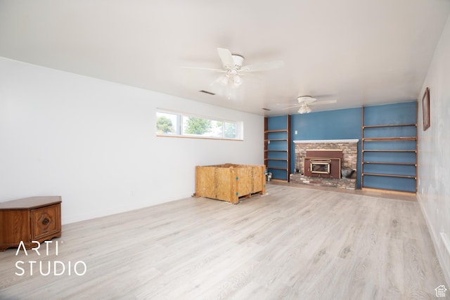 living room featuring ceiling fan, a fireplace, built in features, and light wood-type flooring