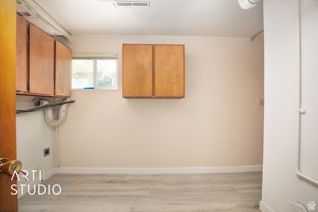 laundry room with electric dryer hookup, cabinets, and light wood-type flooring