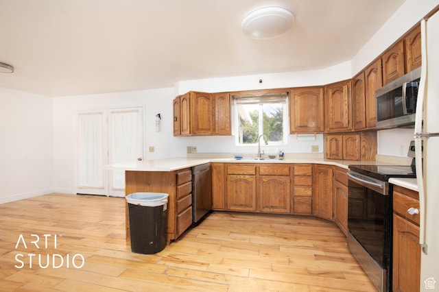 kitchen with light hardwood / wood-style floors, sink, stainless steel appliances, and kitchen peninsula