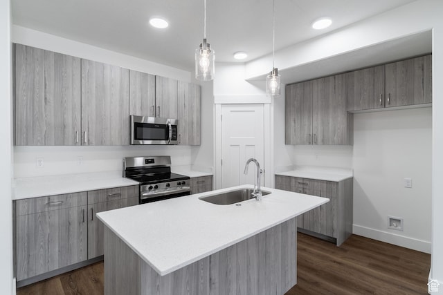 kitchen with stainless steel appliances, light countertops, a sink, and an island with sink