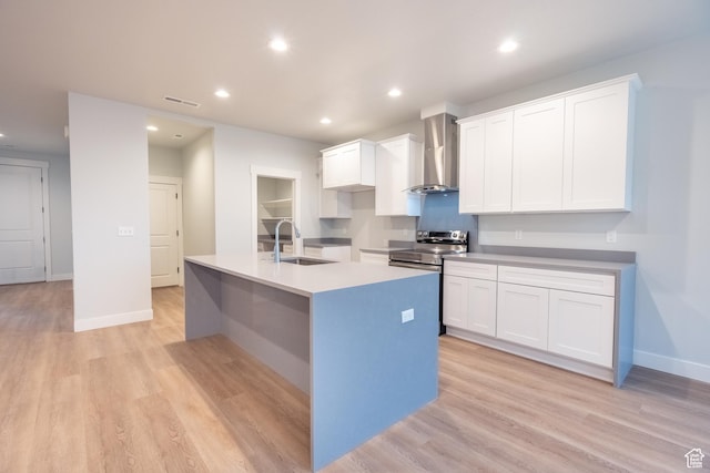 kitchen featuring light wood-type flooring, a kitchen island with sink, sink, white cabinets, and wall chimney exhaust hood