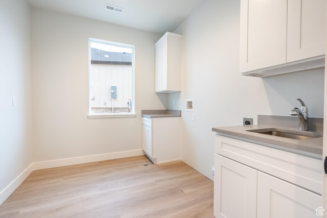 clothes washing area with light hardwood / wood-style flooring, sink, washer hookup, and hookup for an electric dryer