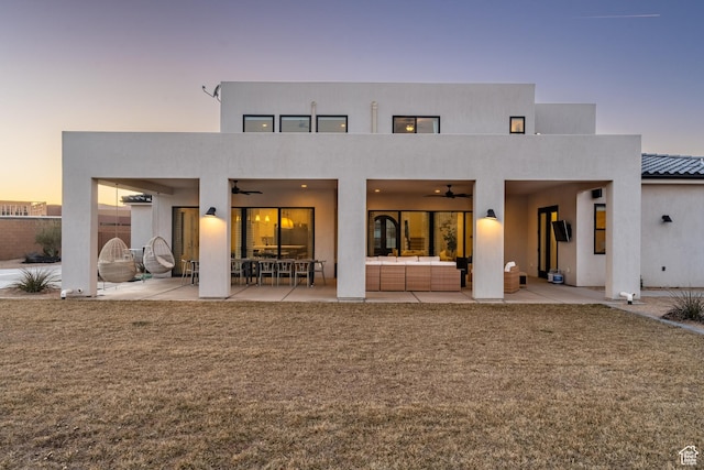 4862 N Sand Cove Cir, St George, UT 84770 - back house at dusk featuring an outdoor hangout area, a lawn, ceiling fan, and a patio area