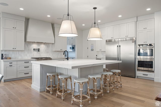 4862 N Sand Cove Cir, St George, UT 84770 - kitchen featuring a center island with sink, premium range hood, built in appliances, and white cabinetry
